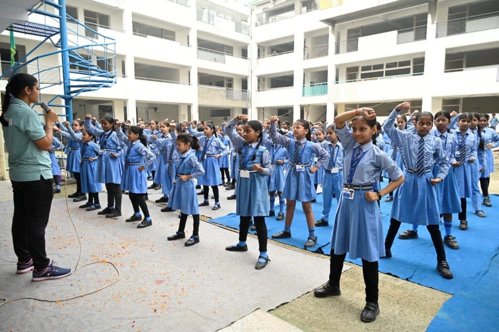 Delhi Police Trainer Guides Self-Defense Drill Delhi Police trainer guiding students through a self-defense drill with a microphone